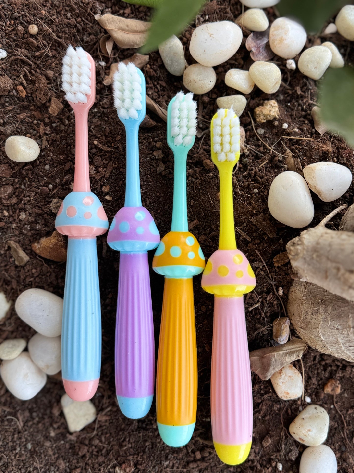 Colorful toothbrushes on a natural background with stones and soil.