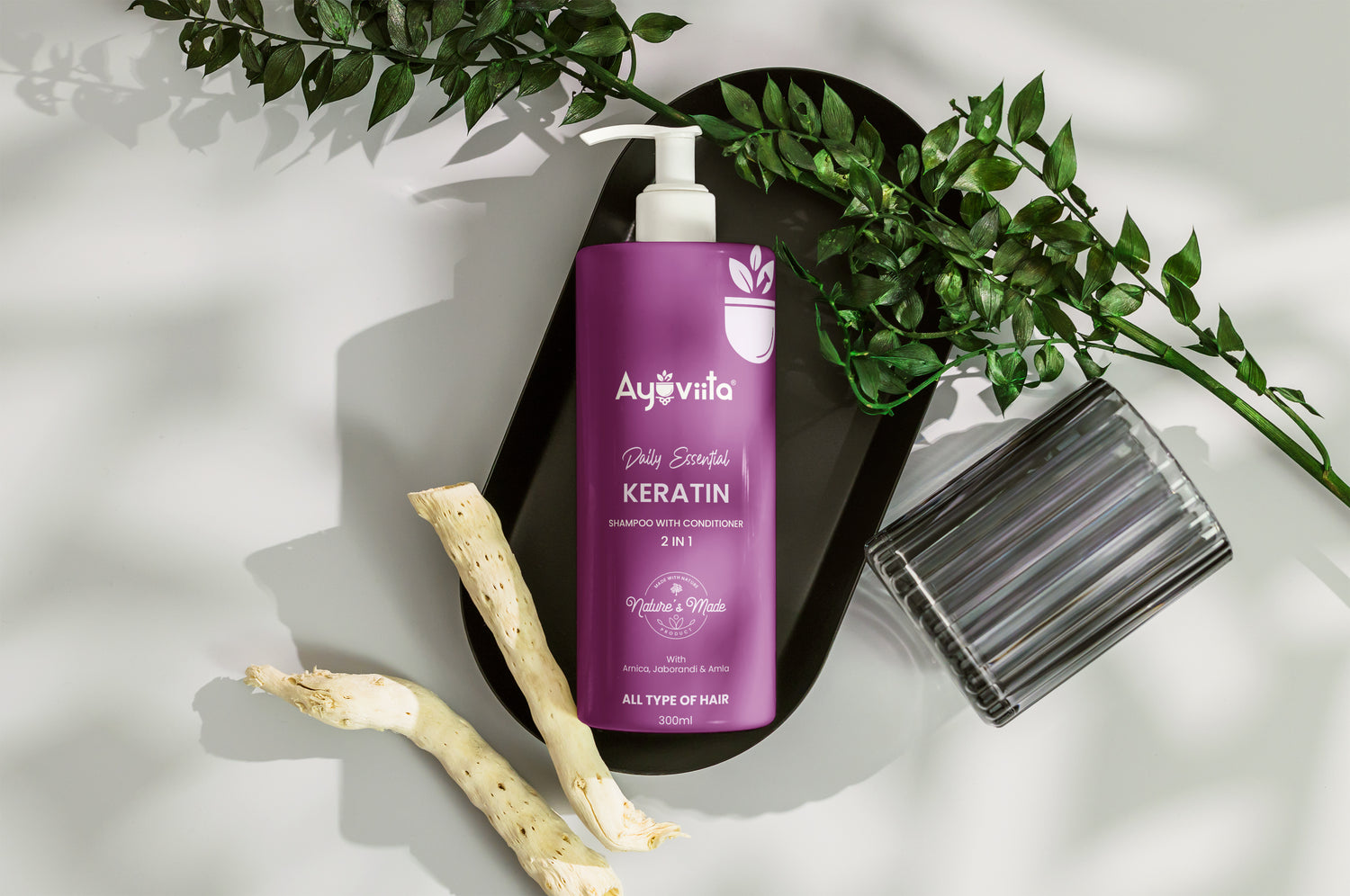 Purple bottle of Ayurvila hair product with green leaves and a plant on a light background