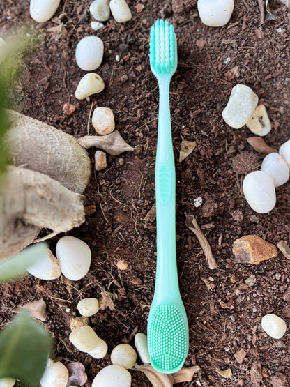 Green toothbrush on a natural background with stones and plants